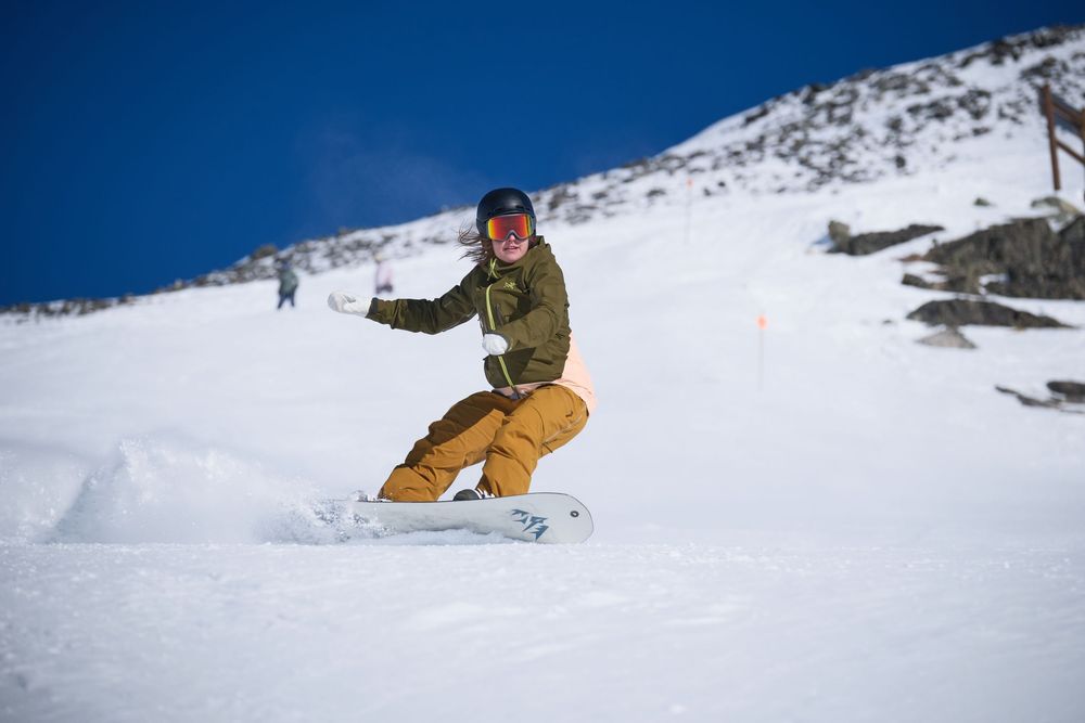 Snowboarder performing aerial tricks and jumps on snowy slopes during winter sports action.