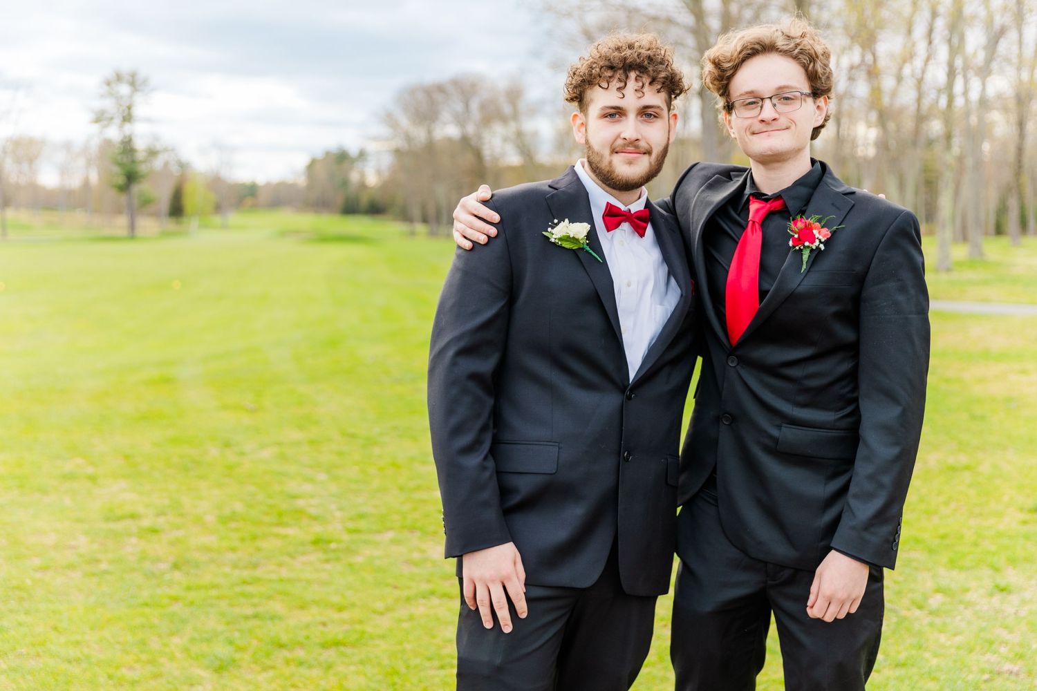 Formal occasion on a spring day with matching red bow ties and black suits.