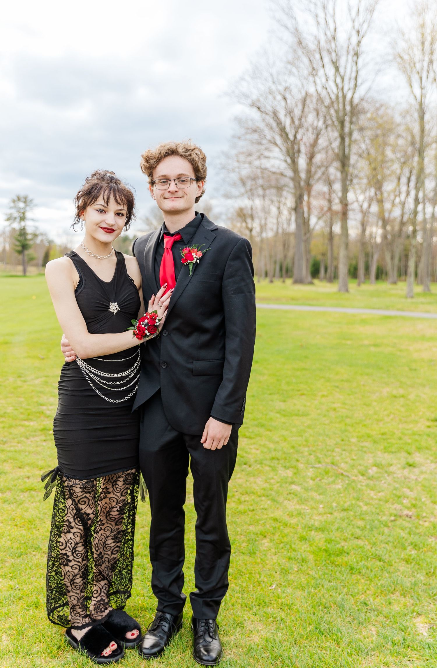 Formal attire with contrasting black and red outfits against a spring landscape.