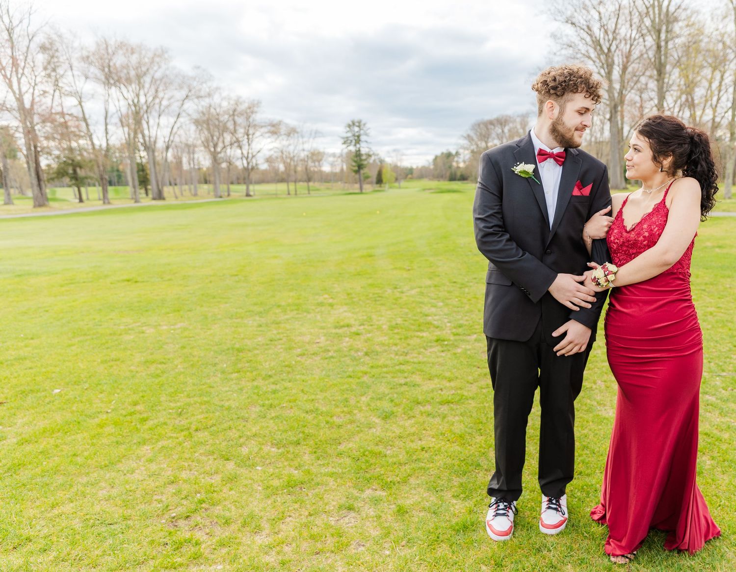Couple in formal wear sharing a moment on green spring grounds.