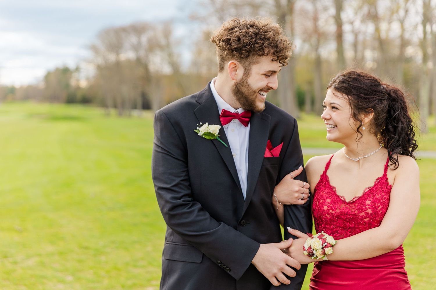 Laughing couple in formal attire sharing a candid moment outdoors.
