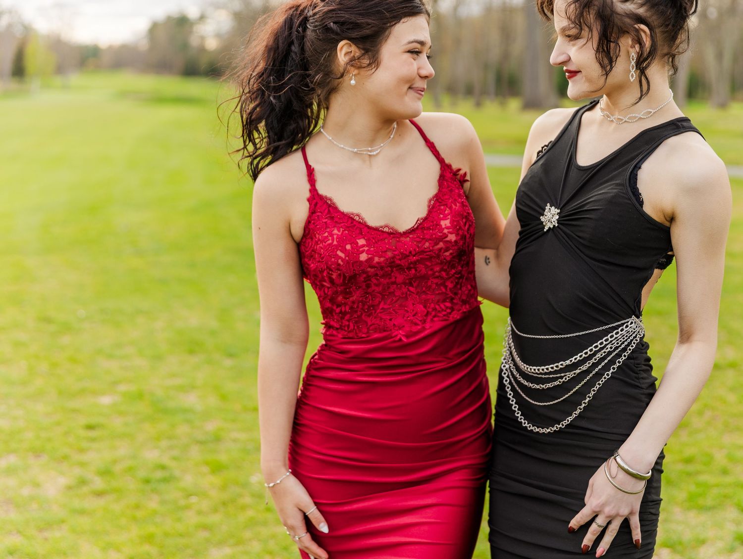 Elegant red and black formal dresses with decorative chain details.