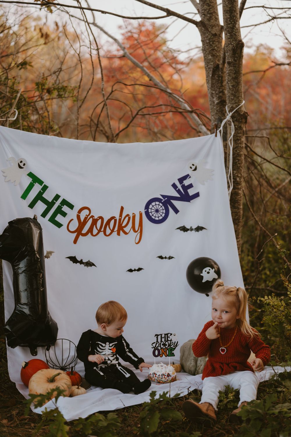 Halloween themed photo setup with spooky banner and children having a festive autumn picnic.
