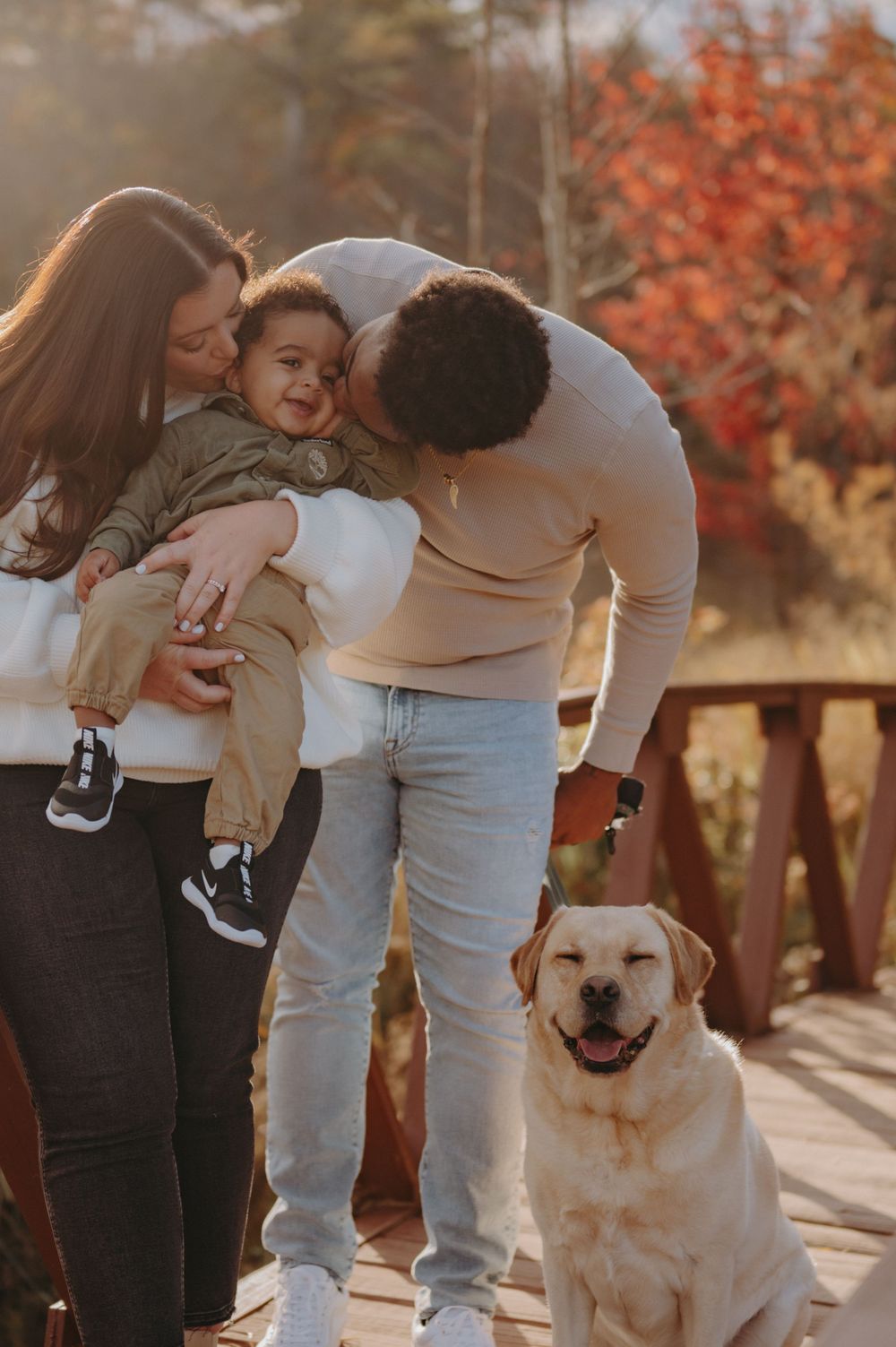A happy family moment with their yellow Labrador dog on a wooden bridge during autumn.