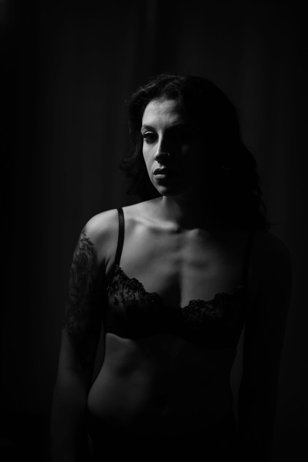 Dramatic black and white boudoir photography with moody lighting and shadows.