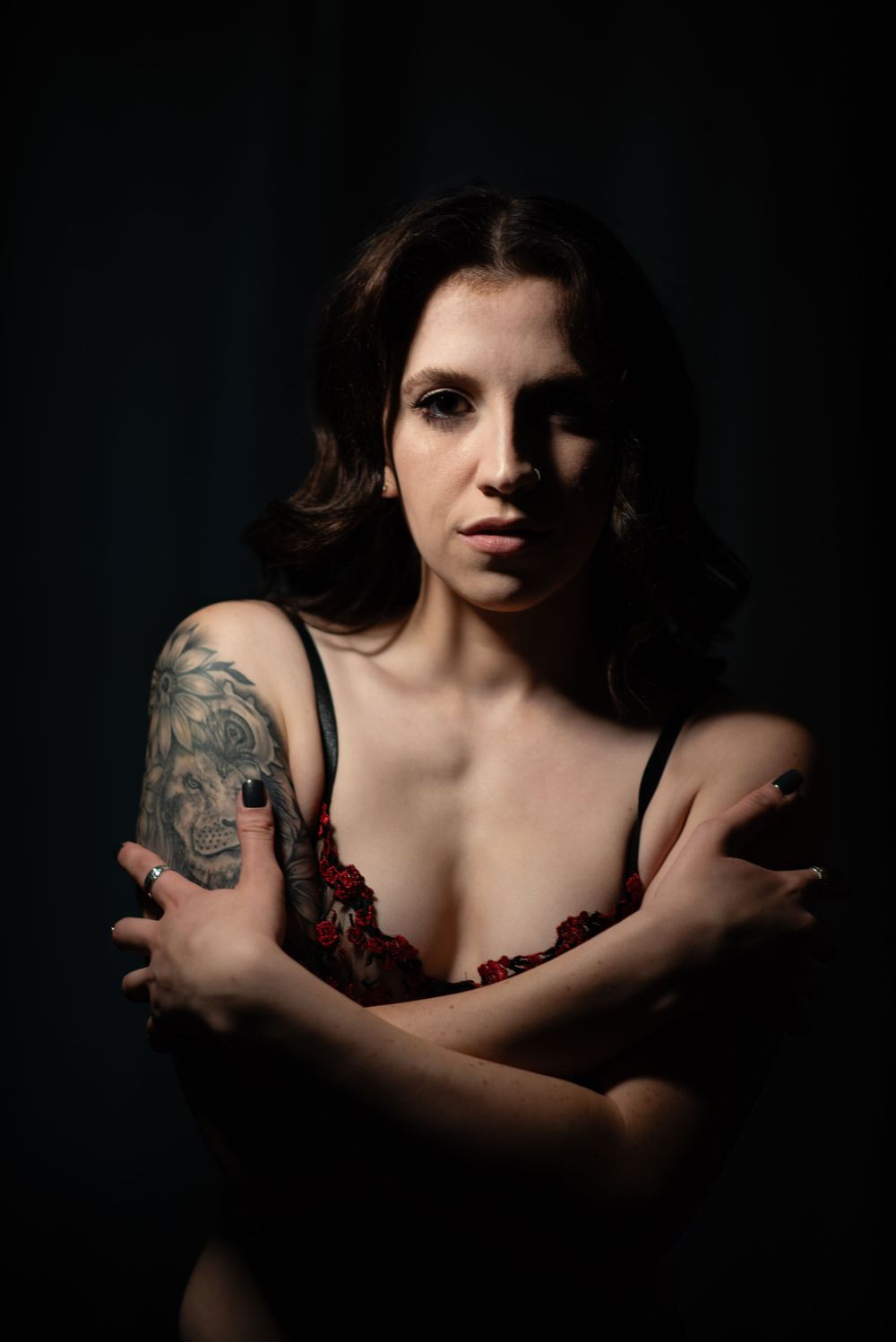 Artistic boudoir portrait showcasing tattoo art in dramatic low-key lighting.