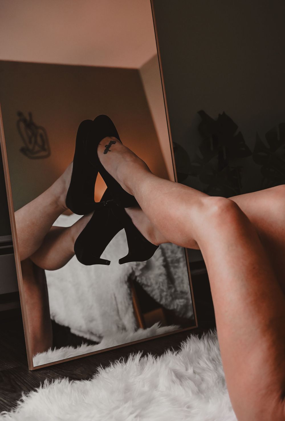 Artistic boudoir photo series with black heels on white fur backdrop.