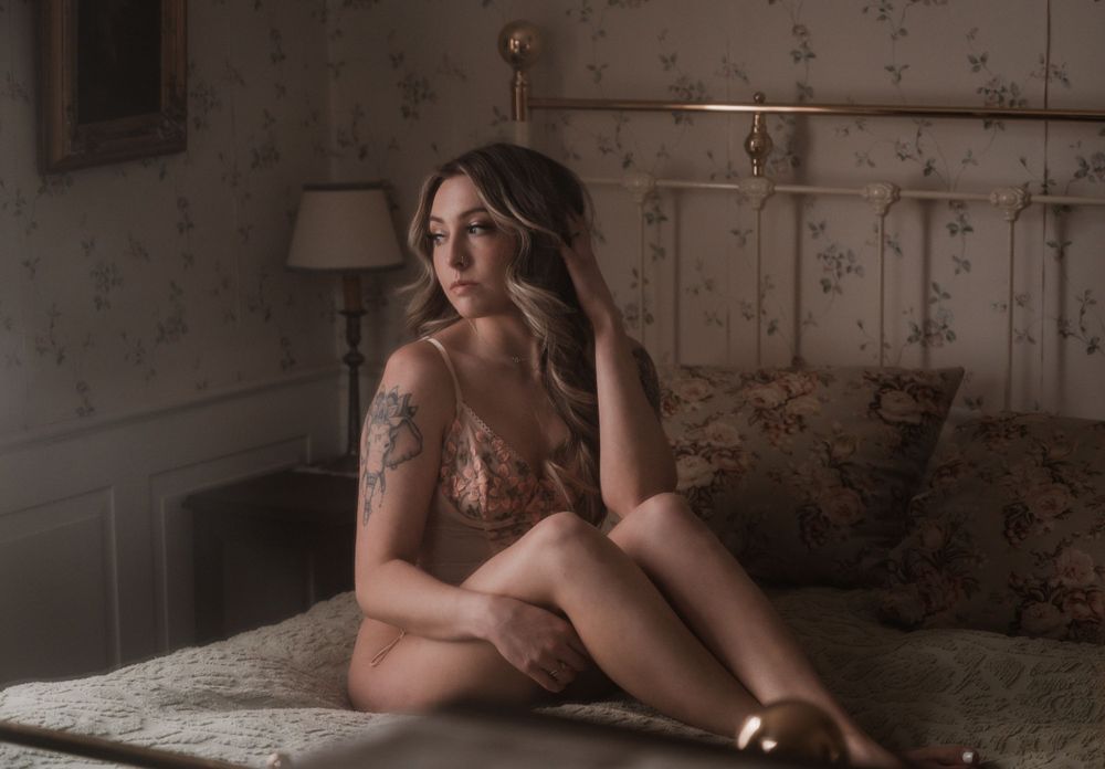 Moody boudoir photography in vintage room with natural window lighting.