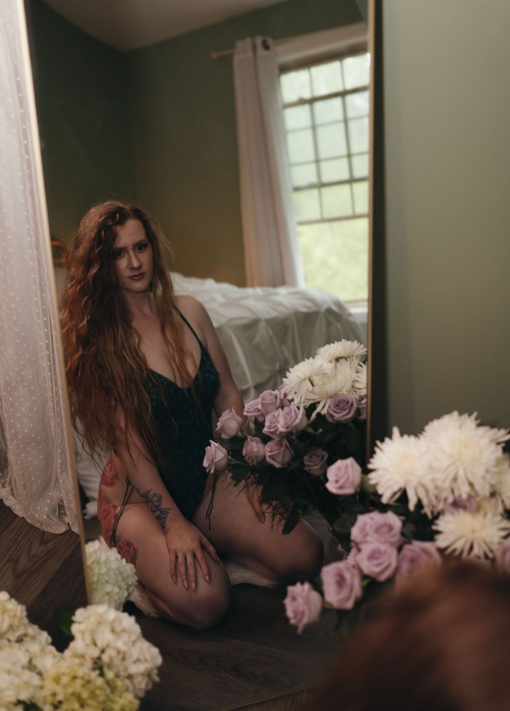 Moody boudoir photo with pink roses and white flowers in soft window light.