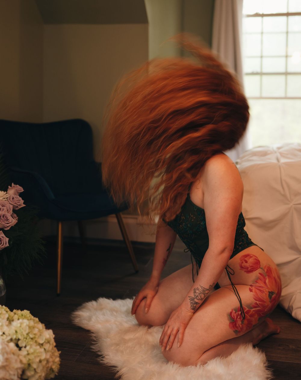 Artistic boudoir photography with roses and white fur in natural window light.