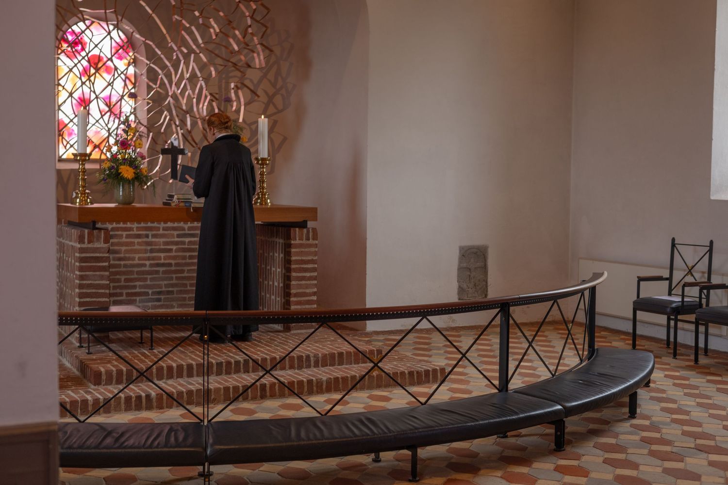 Interior of a church with stained glass windows and curved seating area.