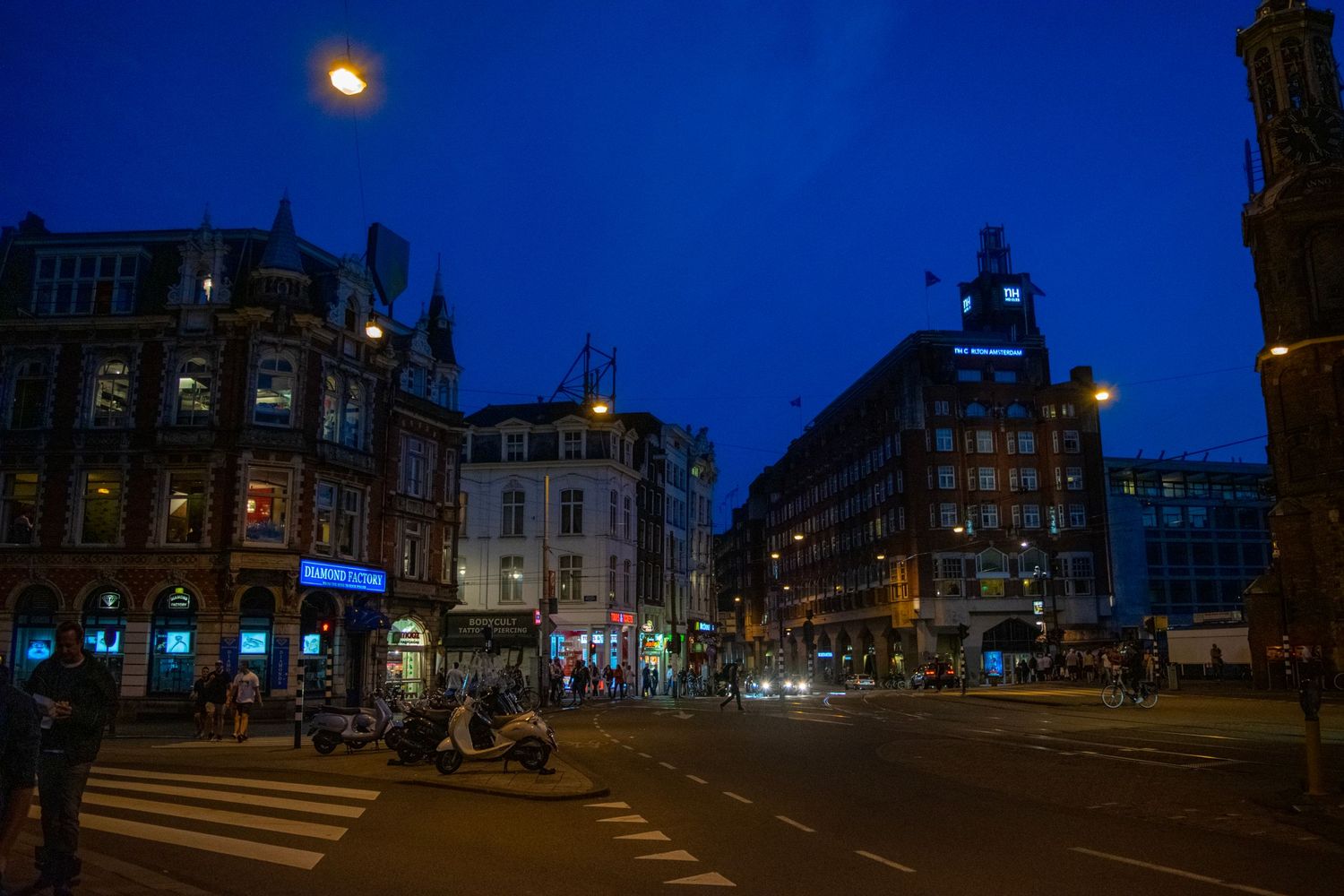 Night scene of Amsterdam city intersection with illuminated historic buildings.