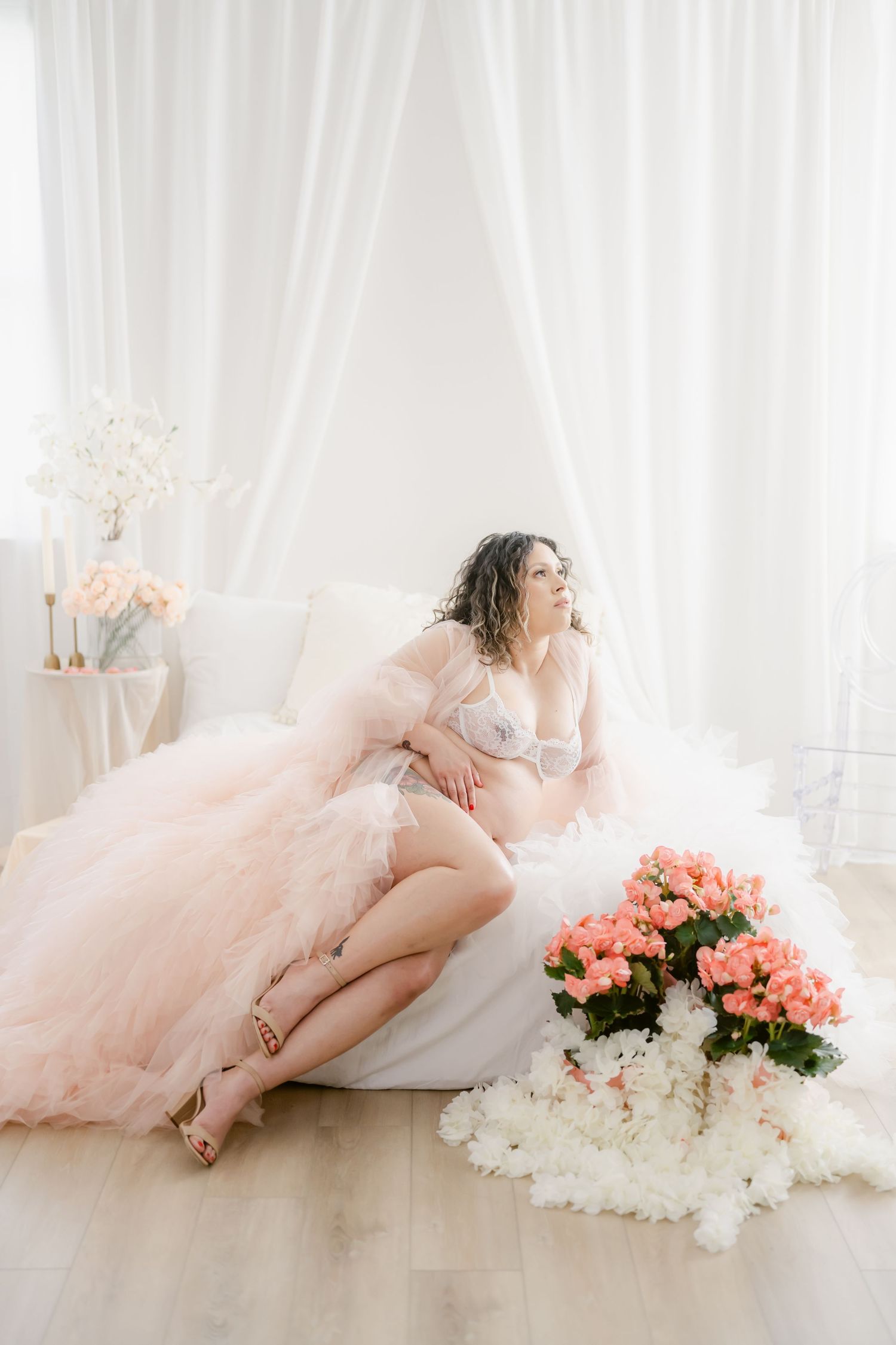Romantic maternity portrait in pink tulle dress with floral arrangement.