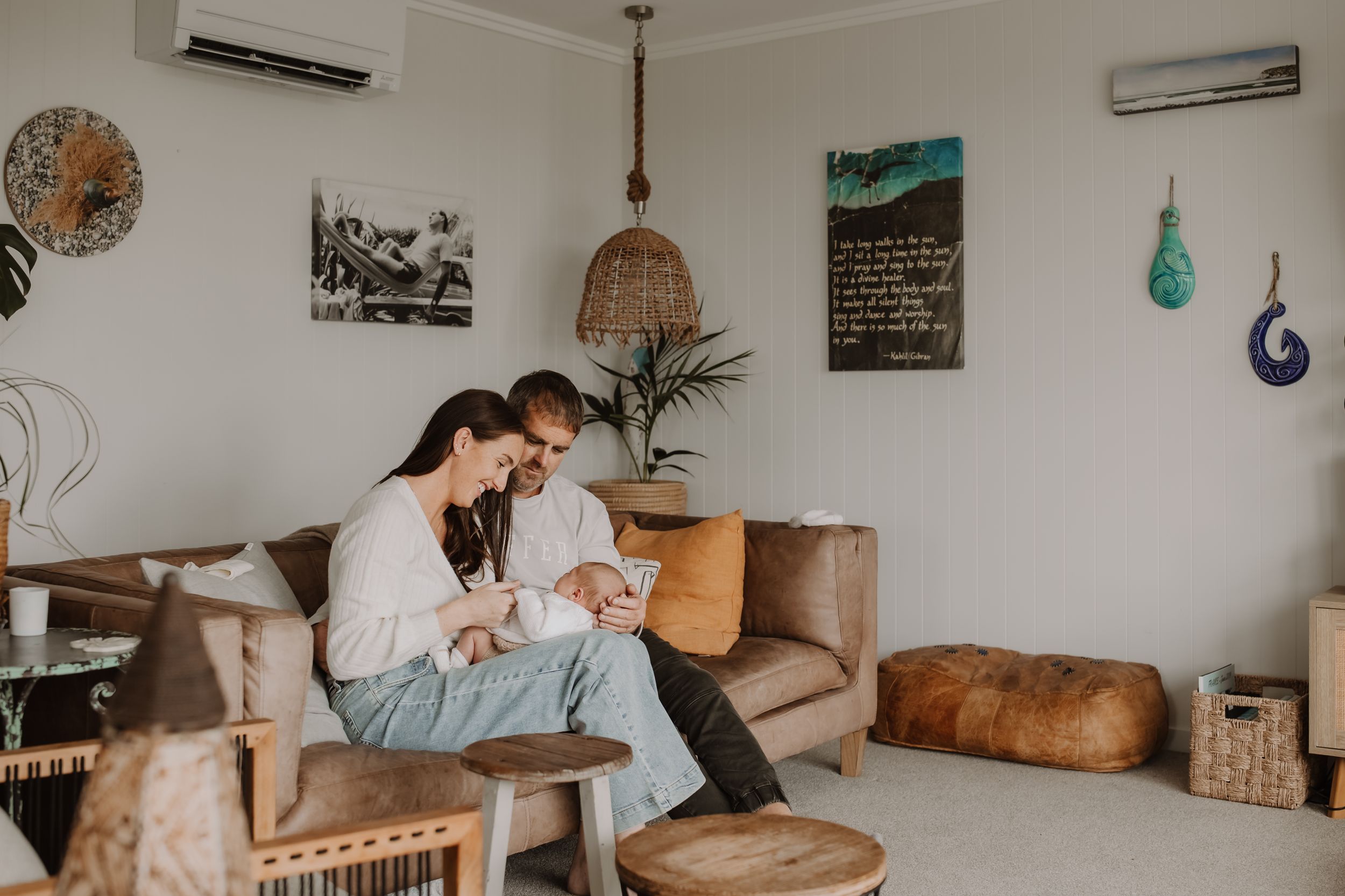 Parents cuddling their newborn baby during a cozy in-home lifestyle photography session in Westport.