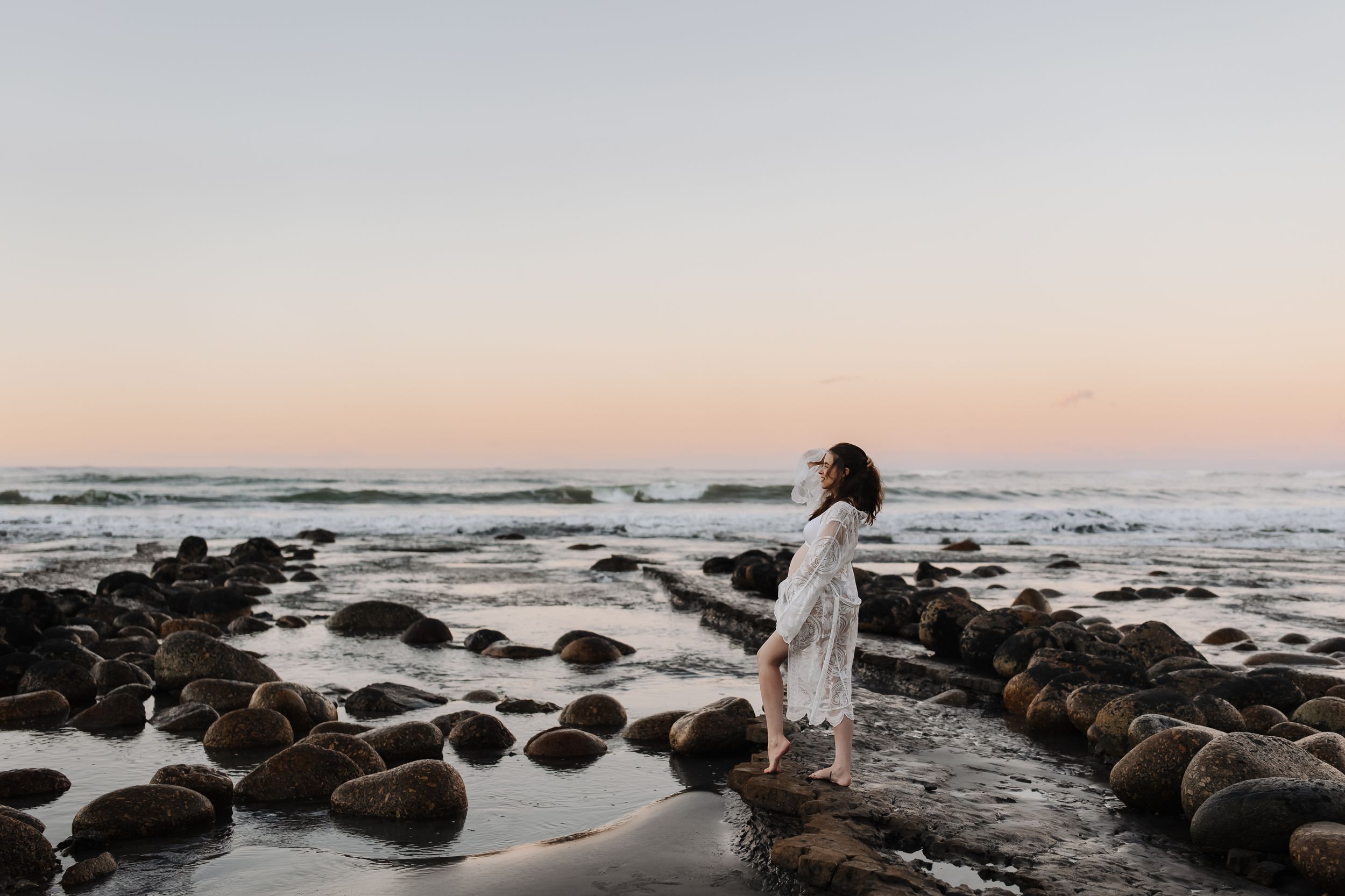 Maternity portrait of expectant mother on golden-hour beach Westport NZ