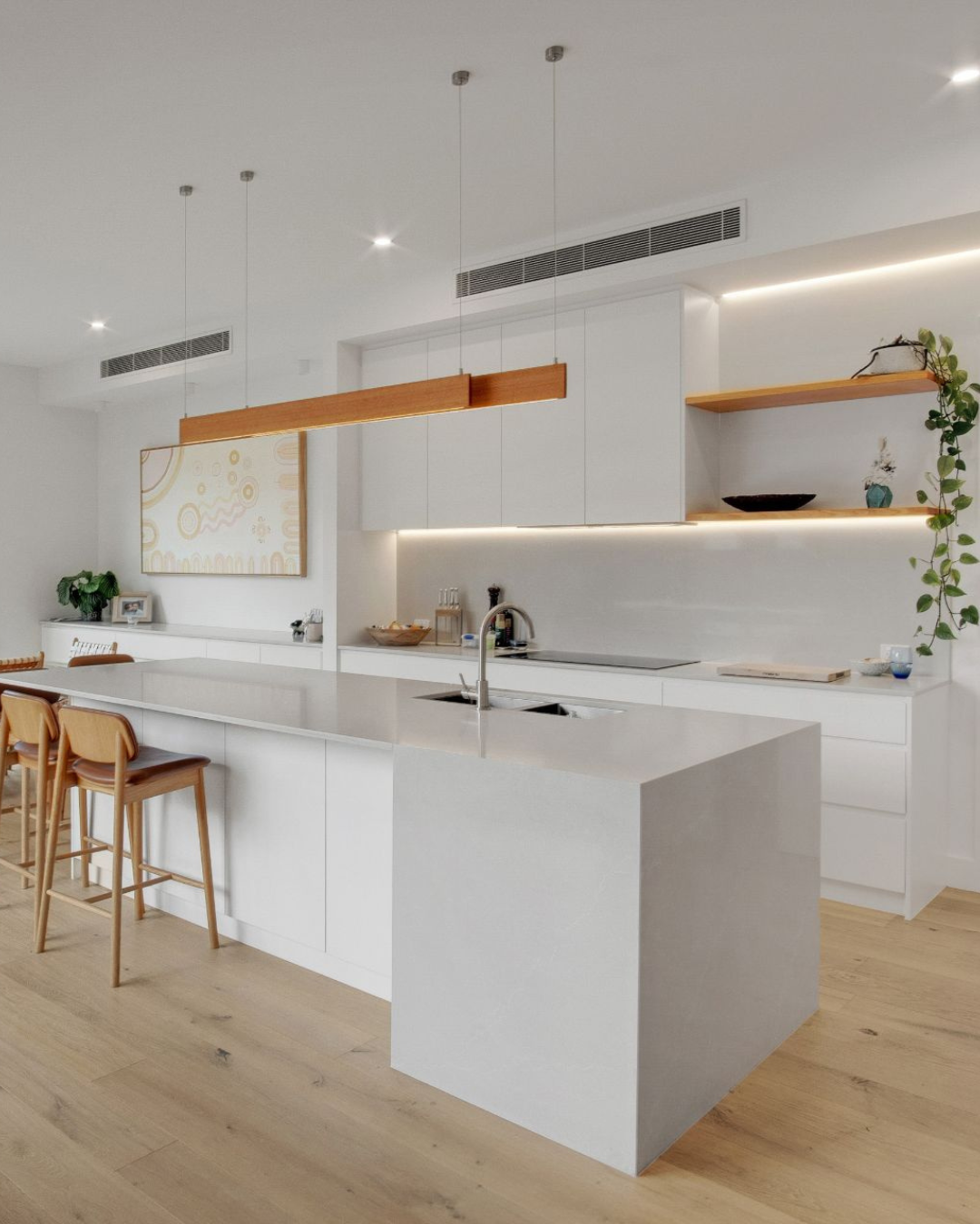 Bright modern kitchen with white countertops, wooden accents, and pendant lighting.