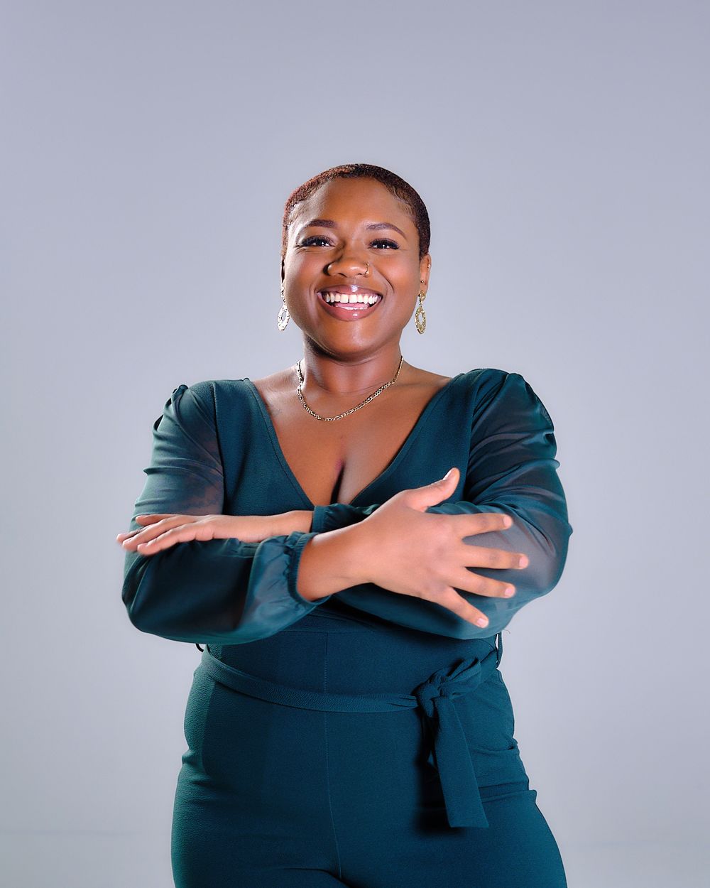 Professional studio portrait in teal dress against light gray background.