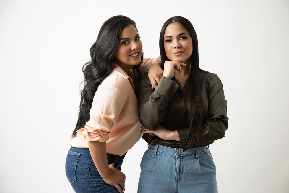 Two people in casual outfits posing together against a white backdrop. Picture taken by Oriana Higuera Photography