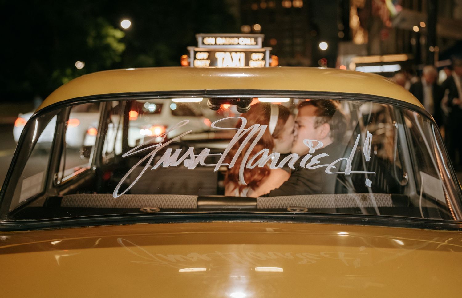 Newlyweds sharing romantic moment in vintage yellow taxi at night.