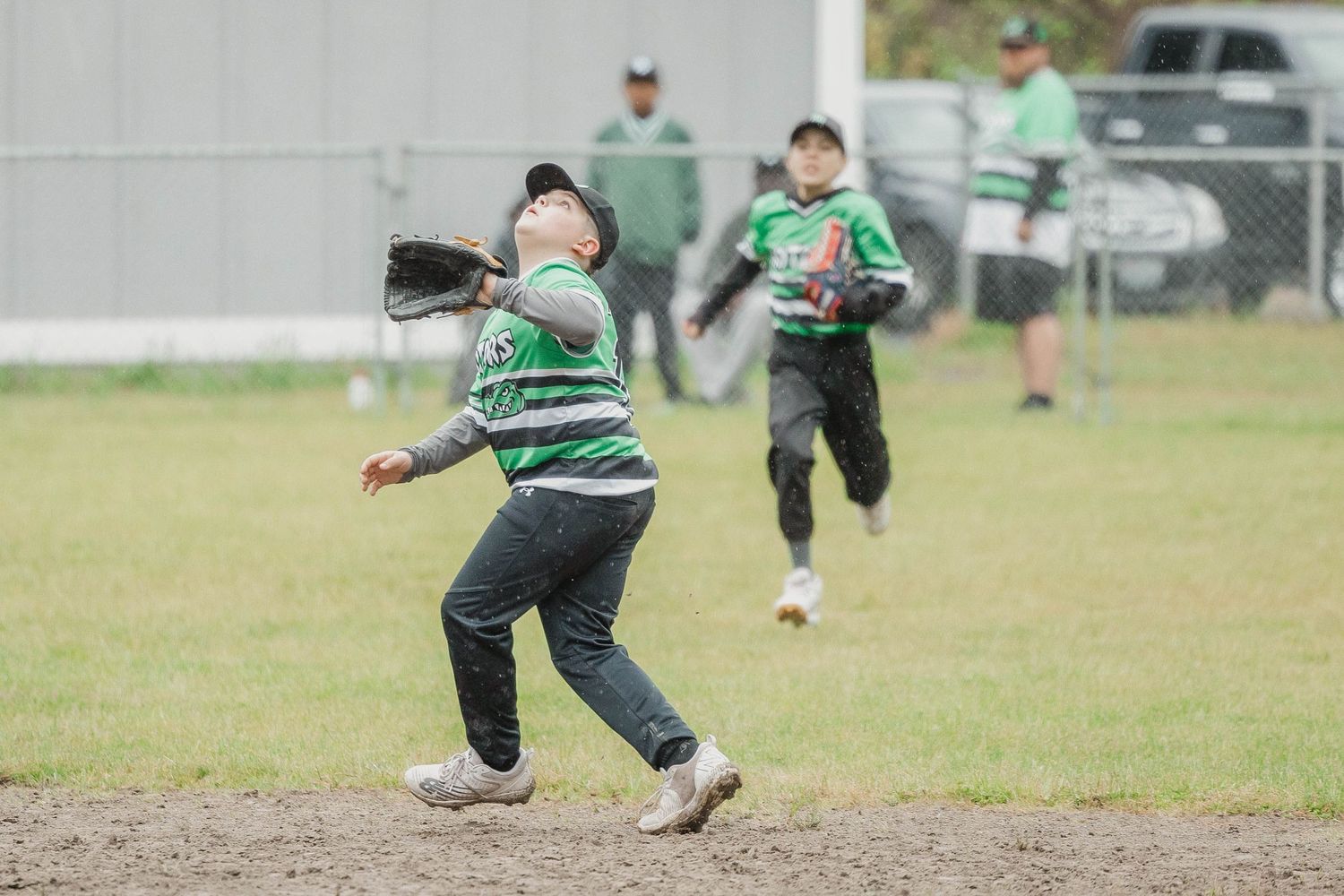Youth baseball players in green striped uniforms running on a field during practice.