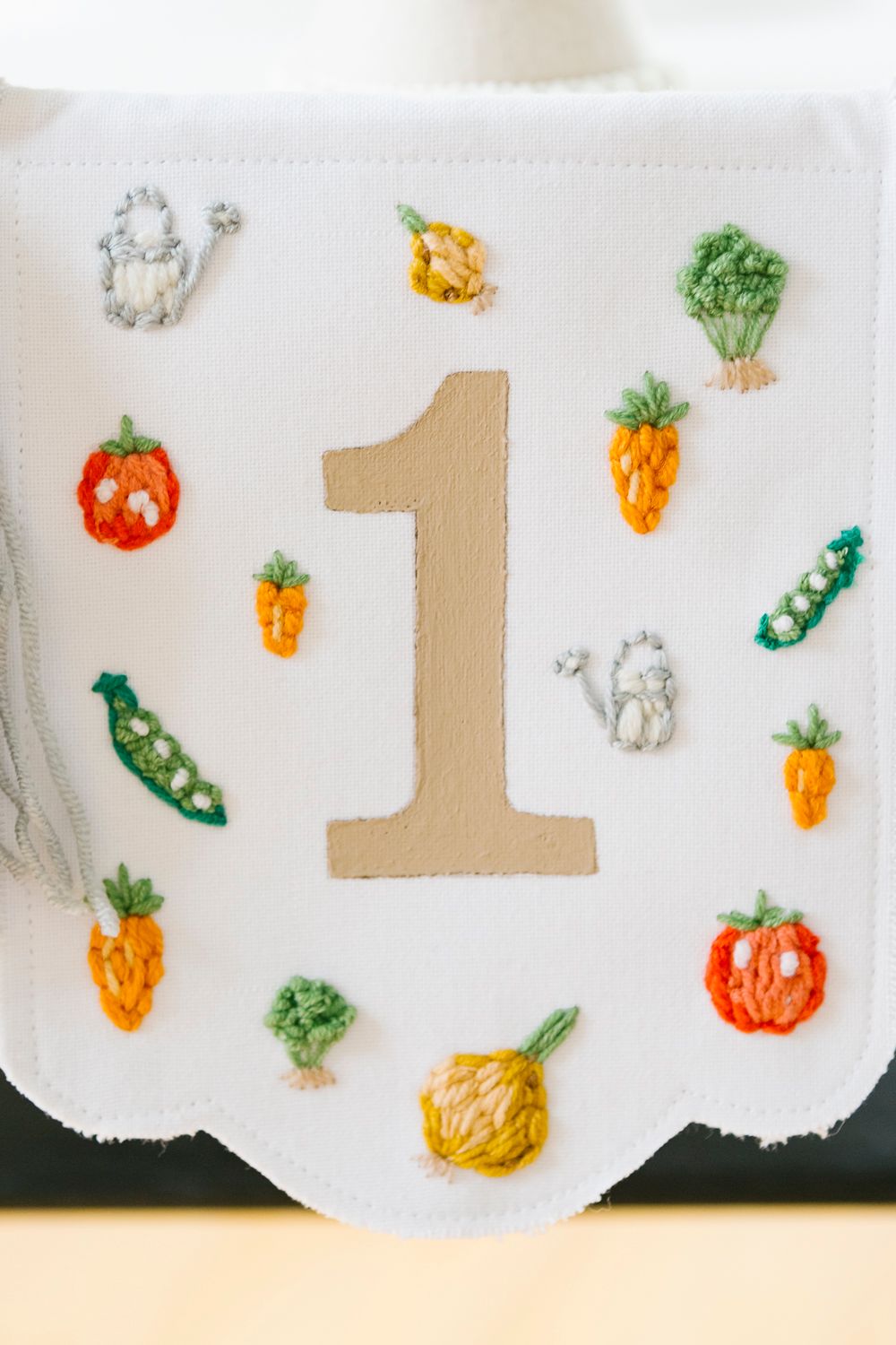 Detail of banner with number one and embroidered veggies, by NYC family photographer Paula Ortiz