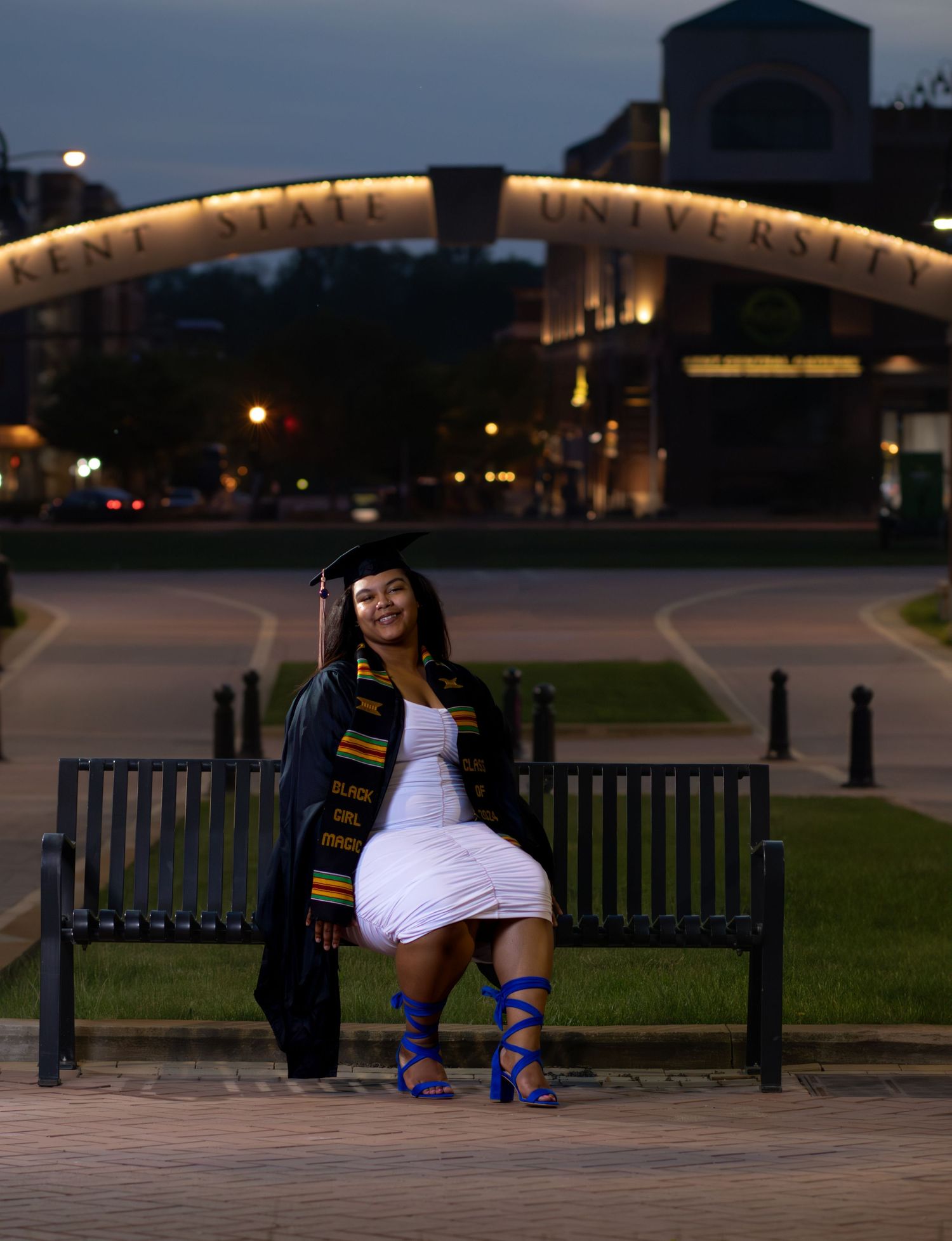 A proud graduate sitting on a bench at Kent State University, showcasing her accomplishment, Black Girl Magic