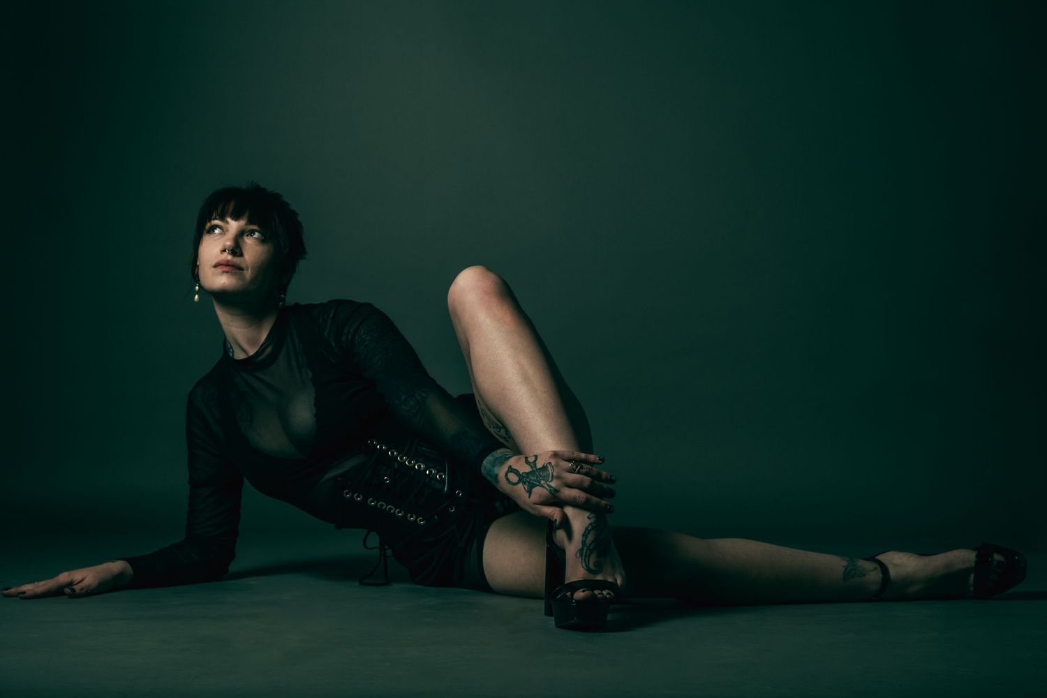 Studio fashion portrait in black outfit against dark green backdrop. boudoir