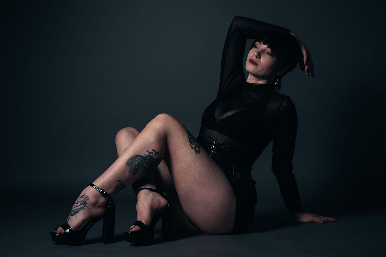 Moody studio portrait featuring black bodysuit and dramatic lighting.