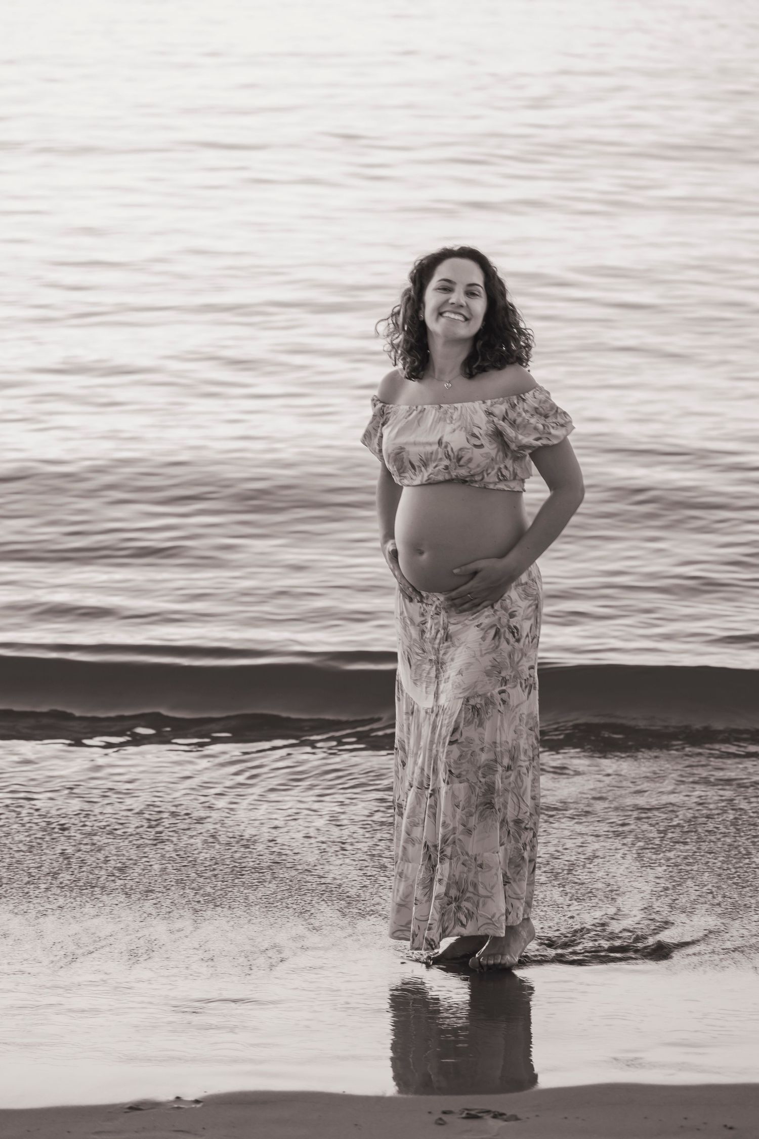 Maternity photoshoot on beach at sunset in black and white.