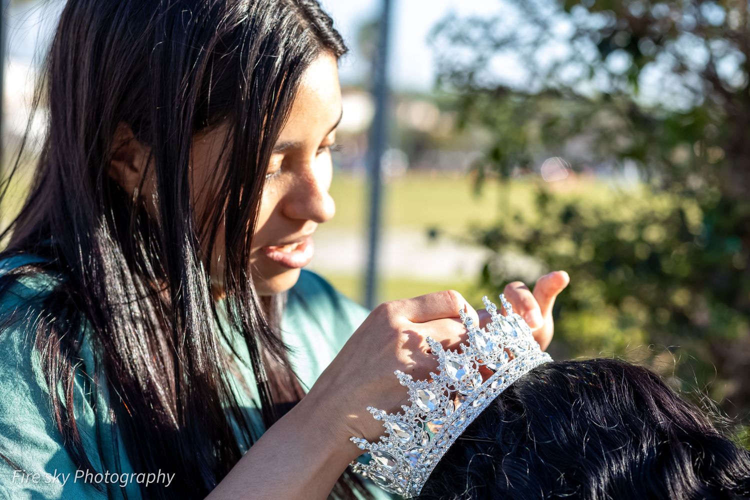 Person with long dark hair focused on texting outdoors on a sunny day.
