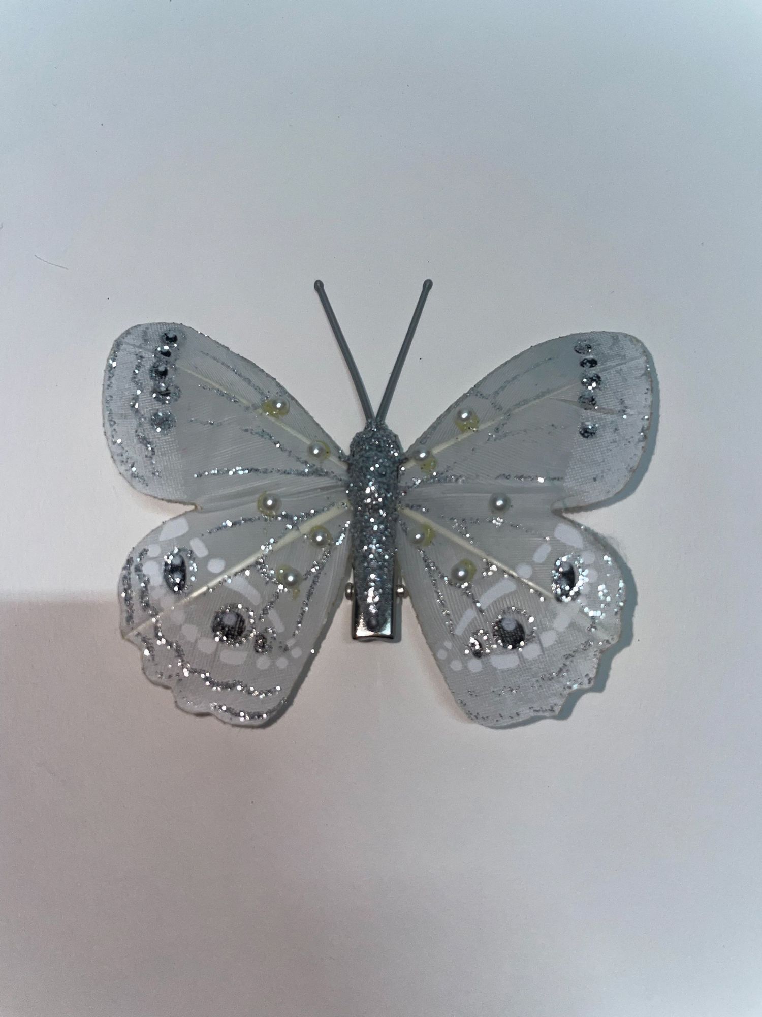A silver glitter butterfly decoration with delicate wing details.