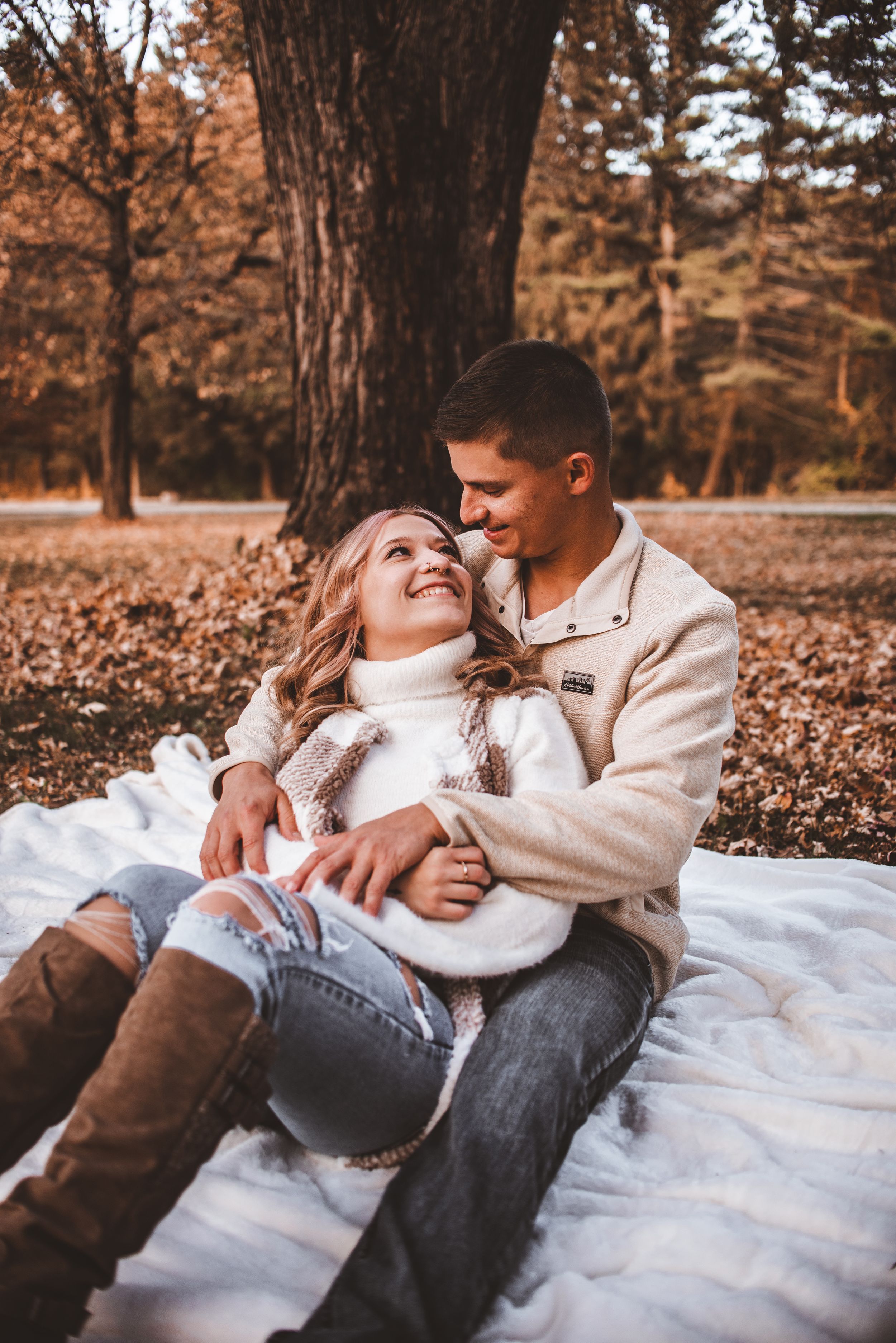A cozy fall picnic scene on a white blanket surrounded by autumn leaves.