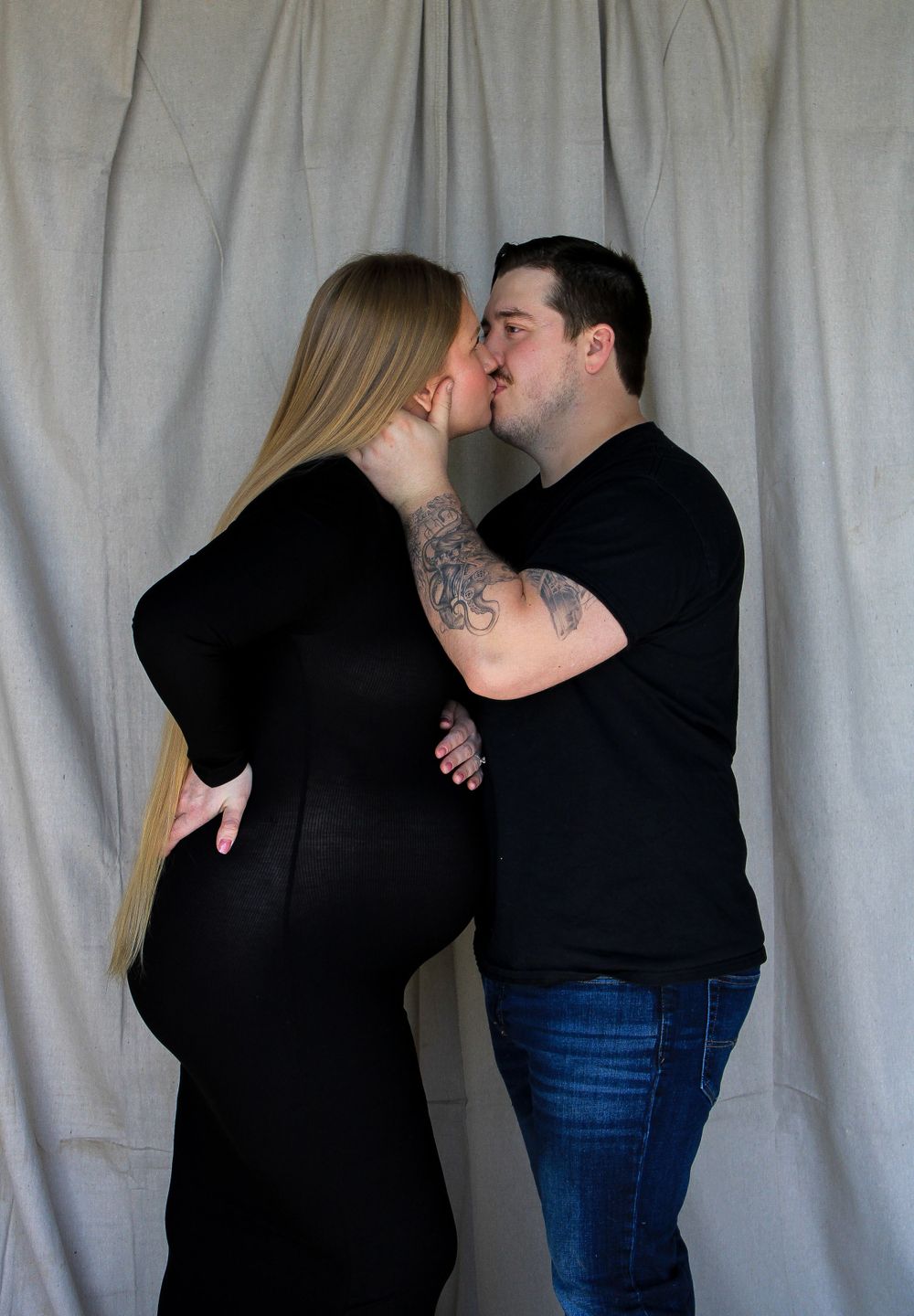 Expecting couple sharing a kiss during a maternity photography session celebrating their growing family.