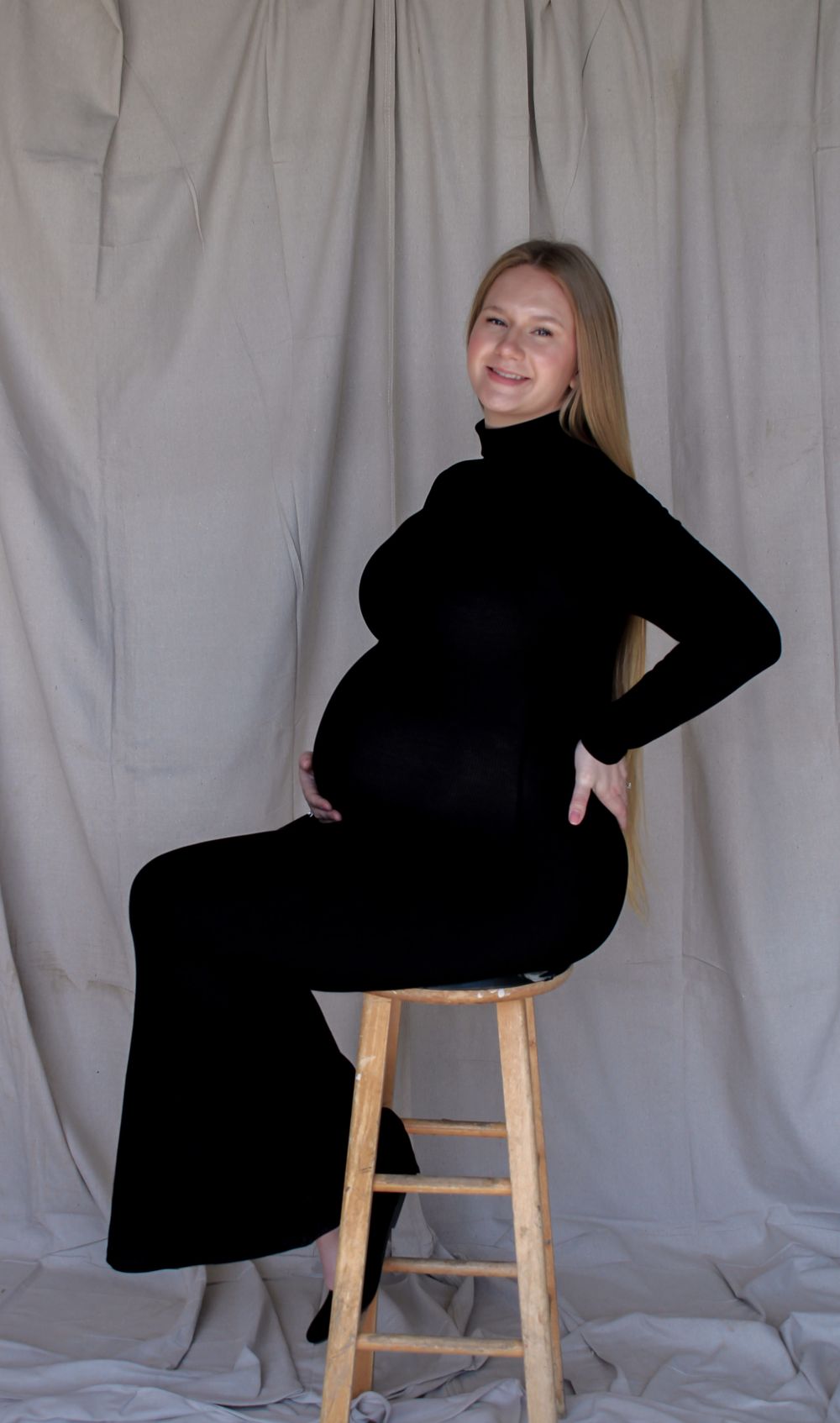 Expecting mother posing on a stool during a studio-style maternity photography session.