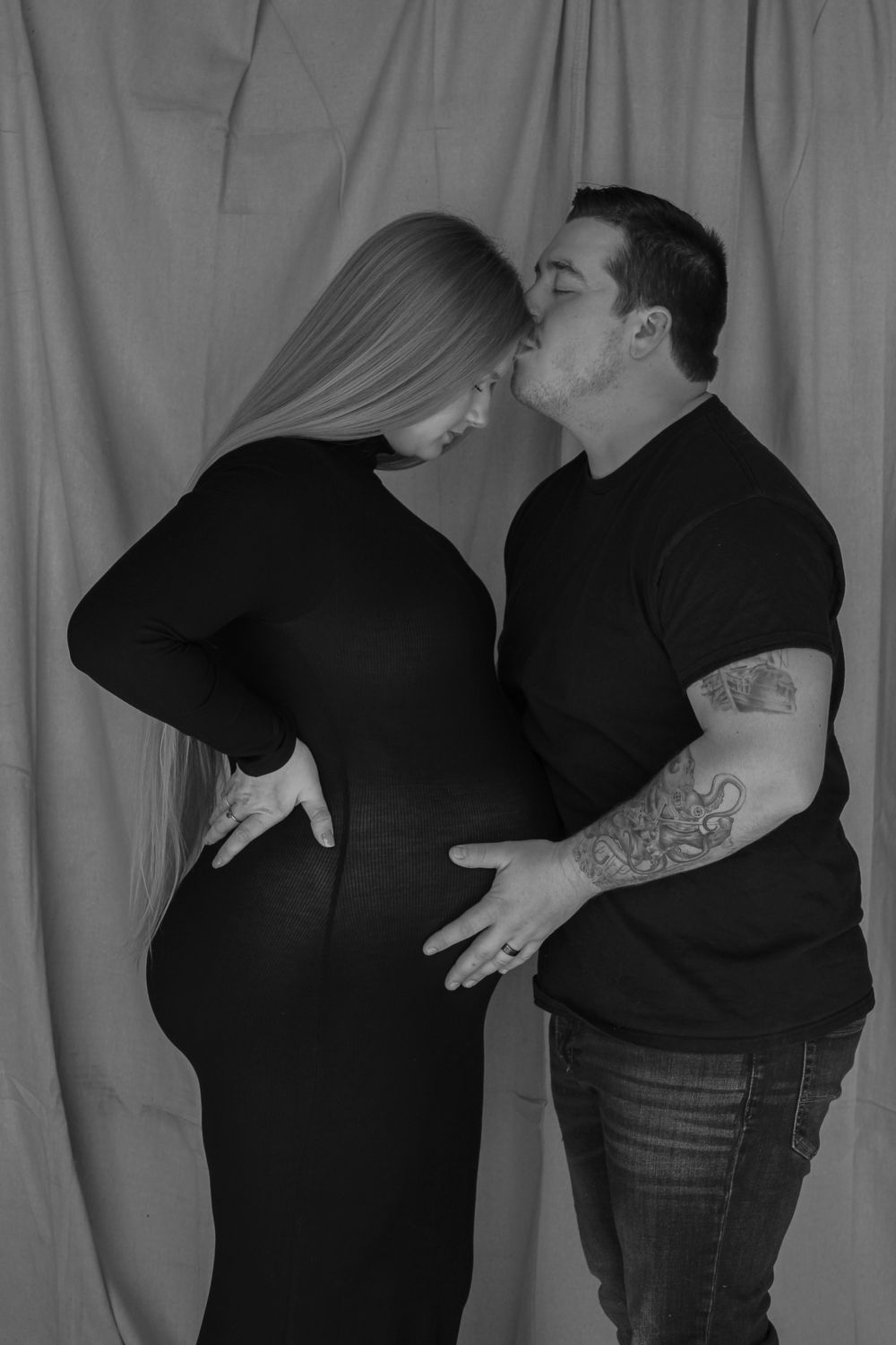 Expecting couple sharing a kiss while celebrating their growing family during a maternity photography session.