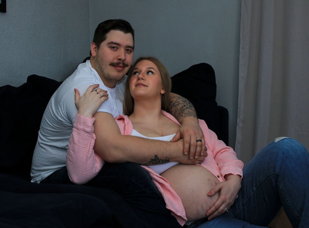 Expecting couple embracing during a cozy indoor maternity photography session.
