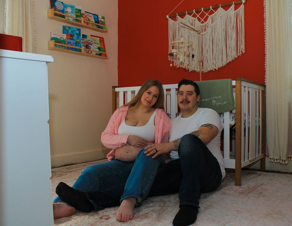 Expecting couple sitting together in their baby's nursery during a lifestyle maternity photography session.