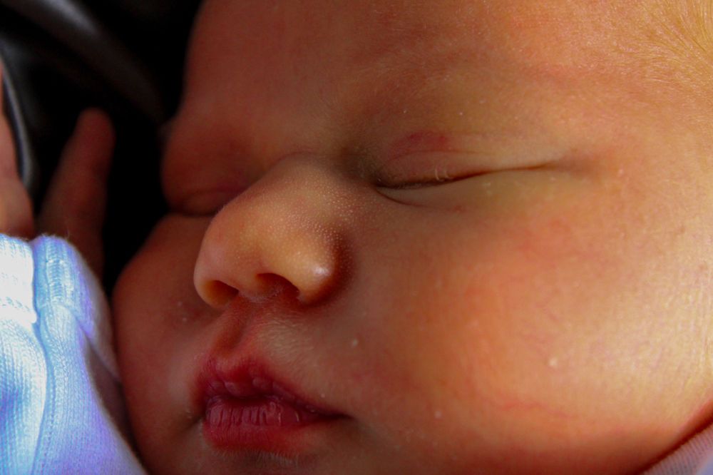 Peacefully sleeping newborn baby cuddled close during a lifestyle newborn photography session.