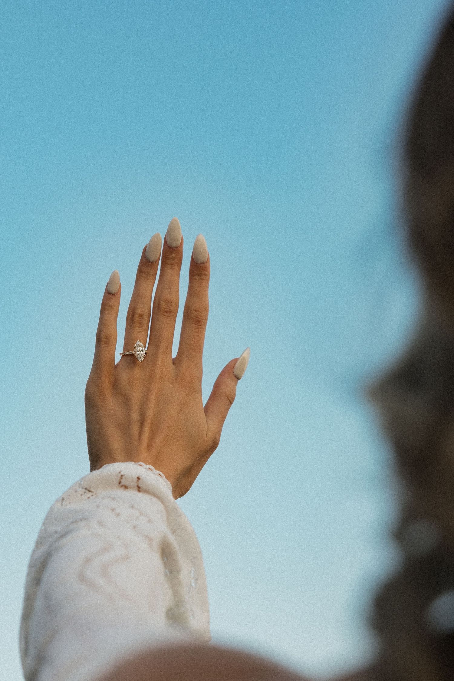 Playful couple holding hands while walking on a dirt road at sunset.