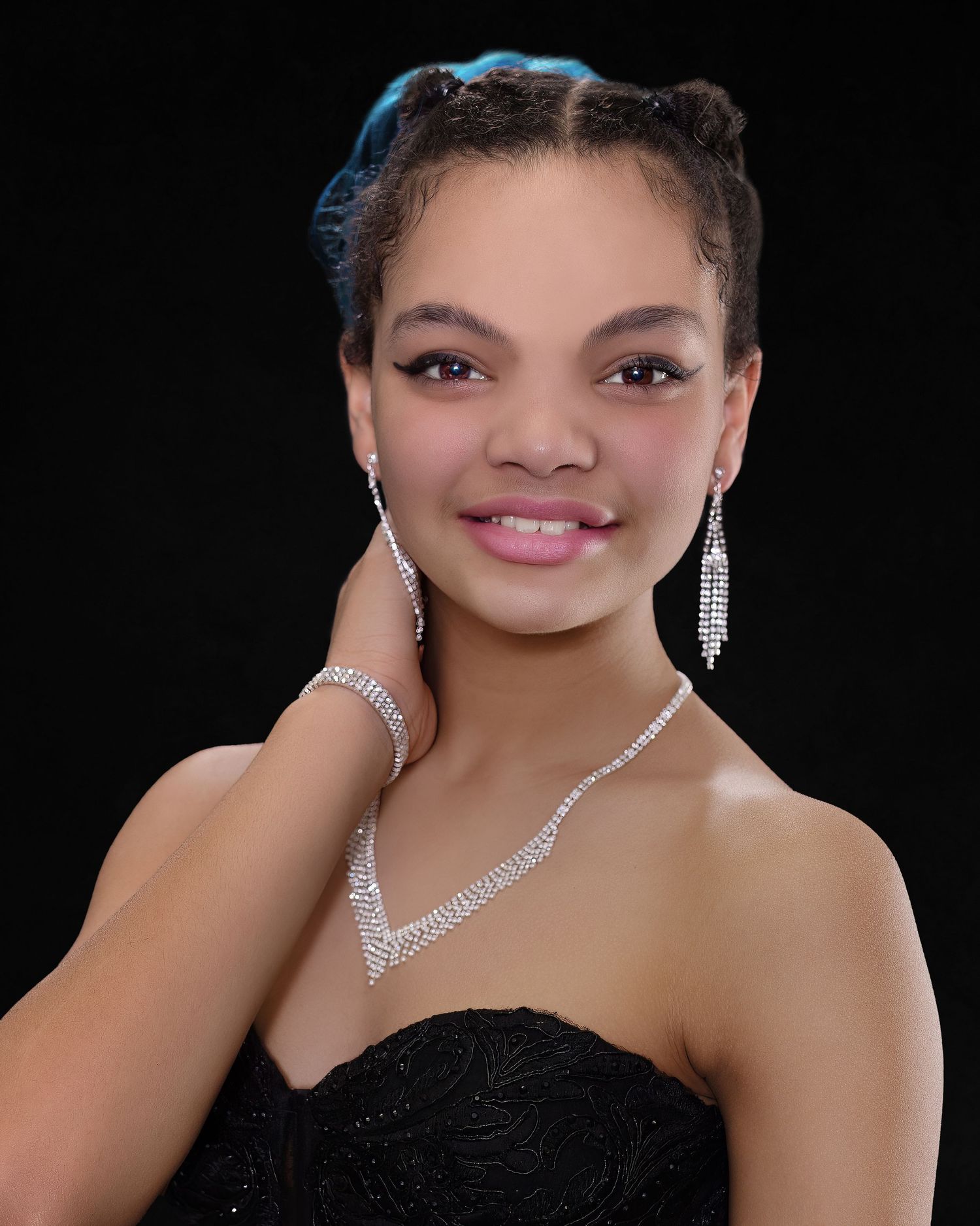 Portrait of someone in a black strapless dress with sparkling diamond jewelry against a dark background.