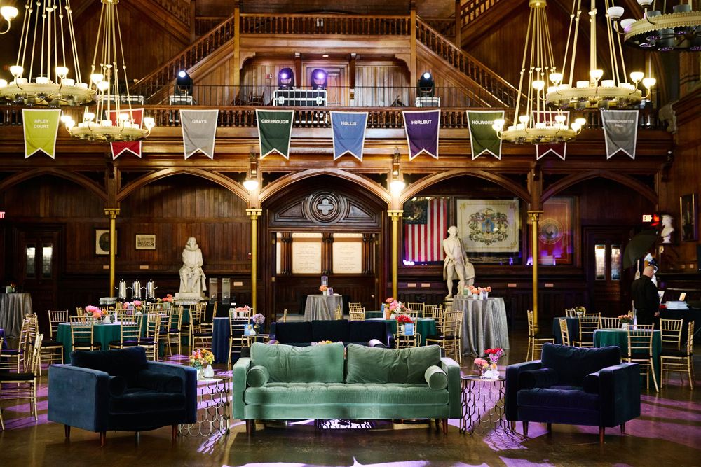 Rustic barn wedding reception venue with vintage furniture, chandeliers and colorful banners decorating the wooden interior.