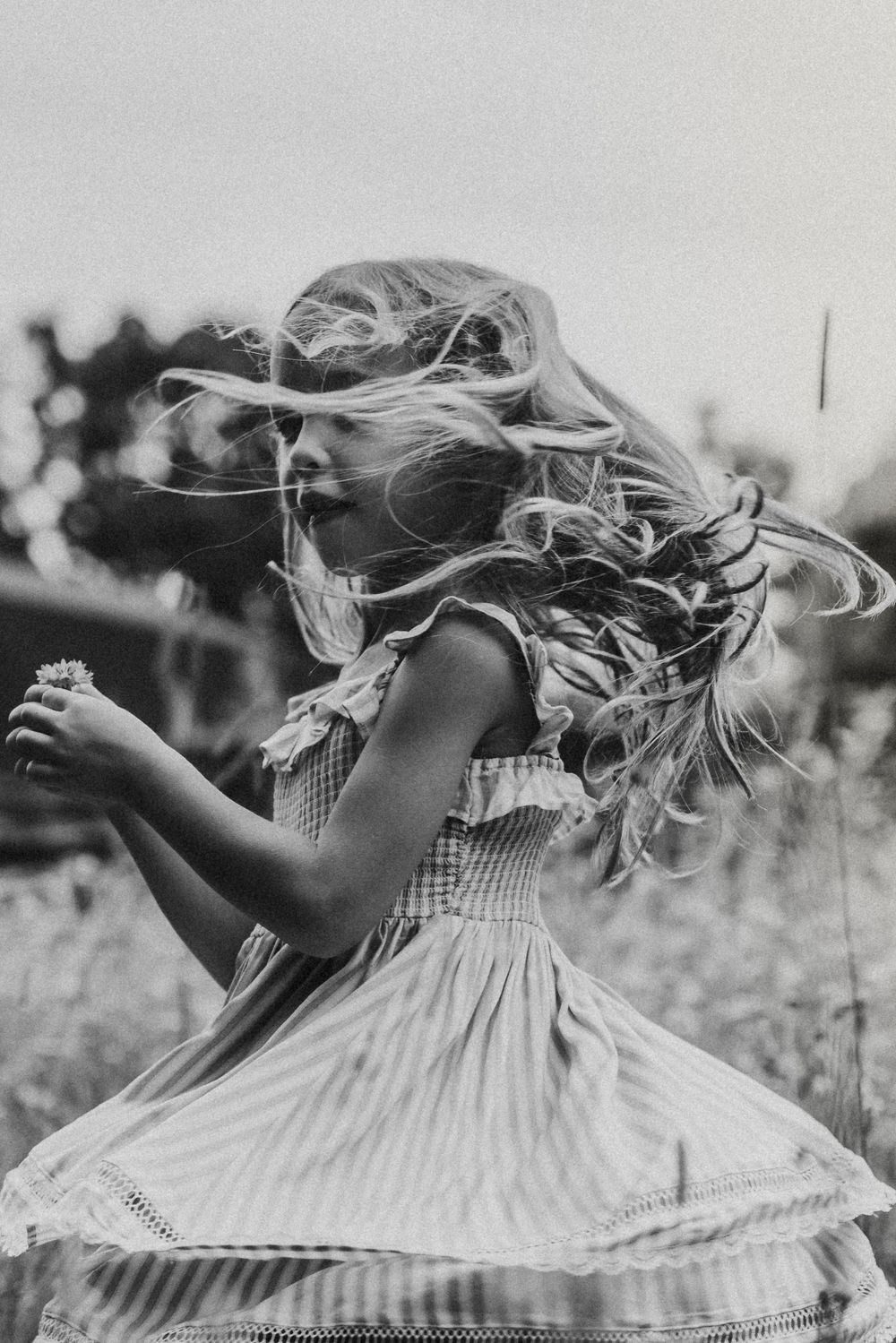 Black and white sequence of someone twirling in a dress with hair flowing in the wind.