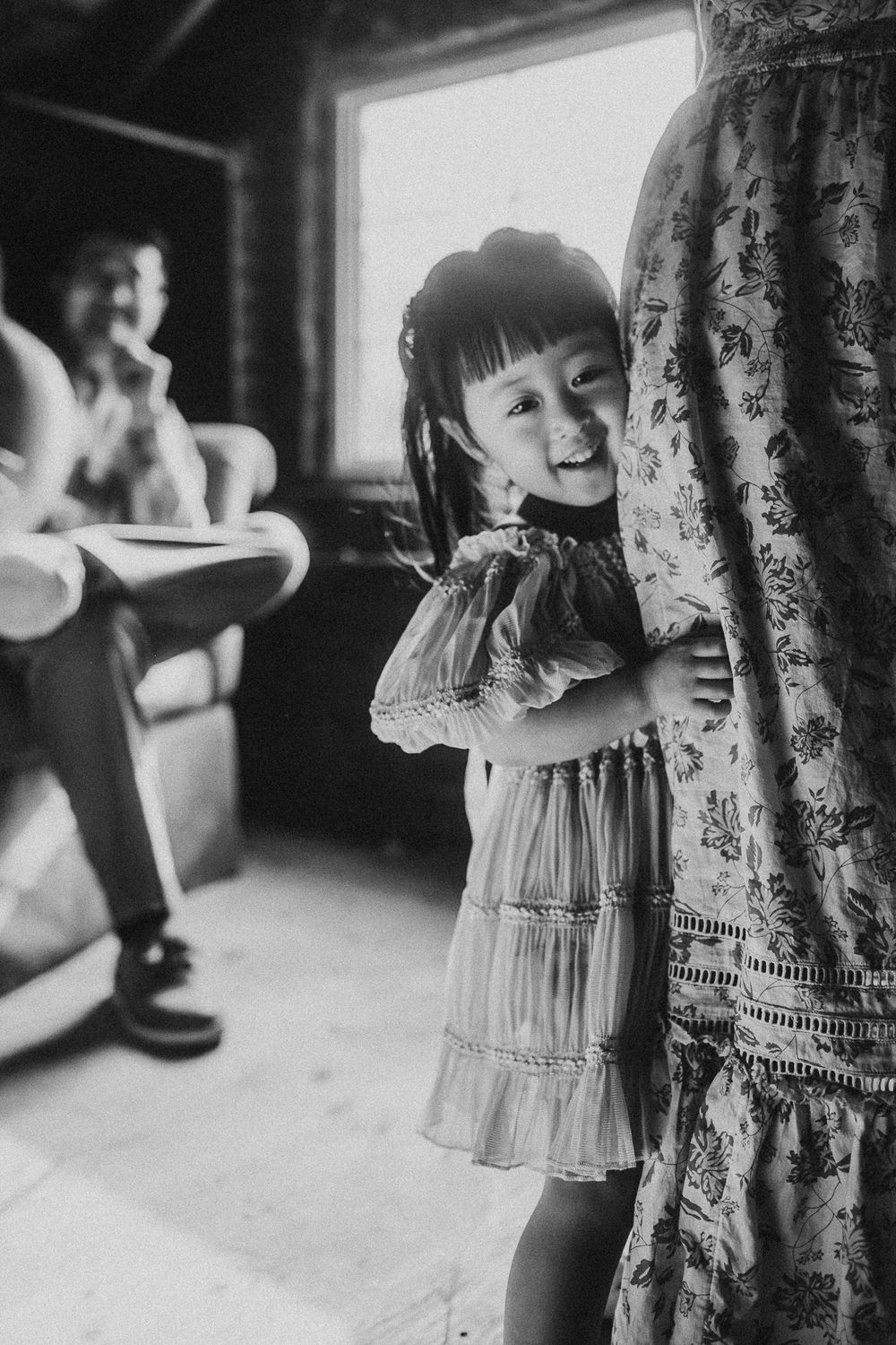 Black and white images showing playful hiding and seeking behind curtains.