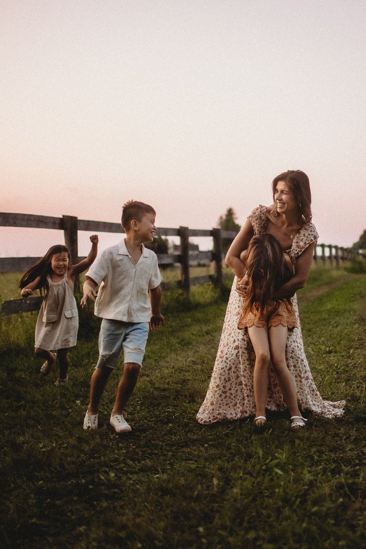 Playful family moments captured in field during golden hour sunset.