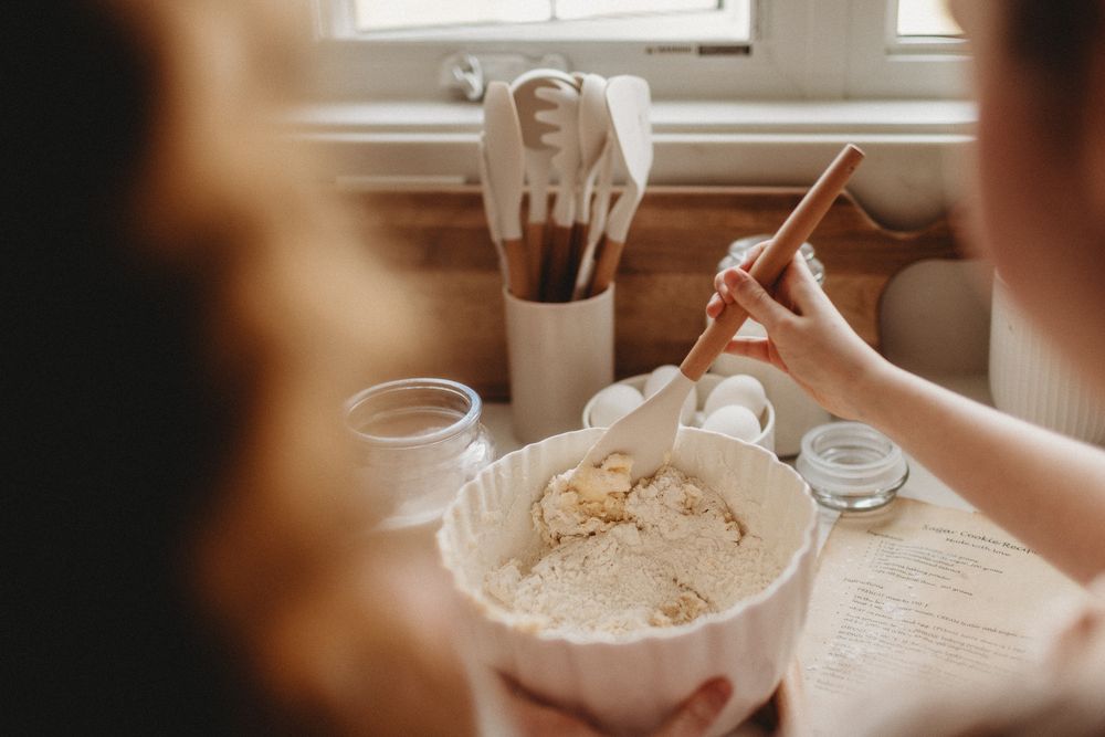Warm sunlit kitchen scene with bowls and baking ingredients being mixed together.