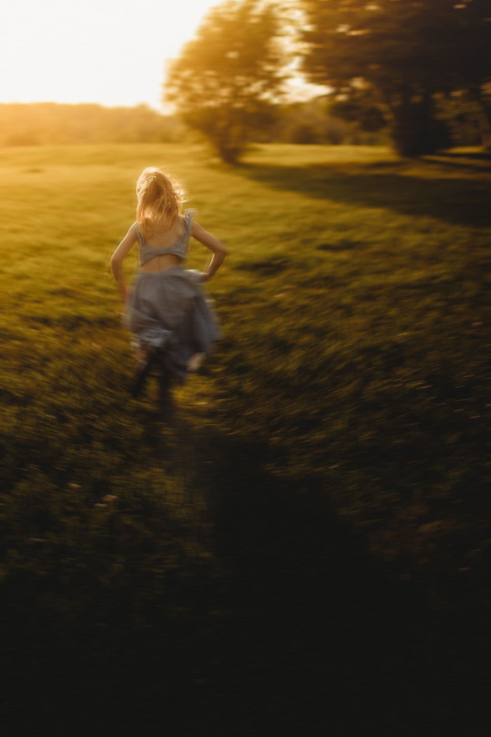 Silhouetted figures running through a sunlit field during golden hour.