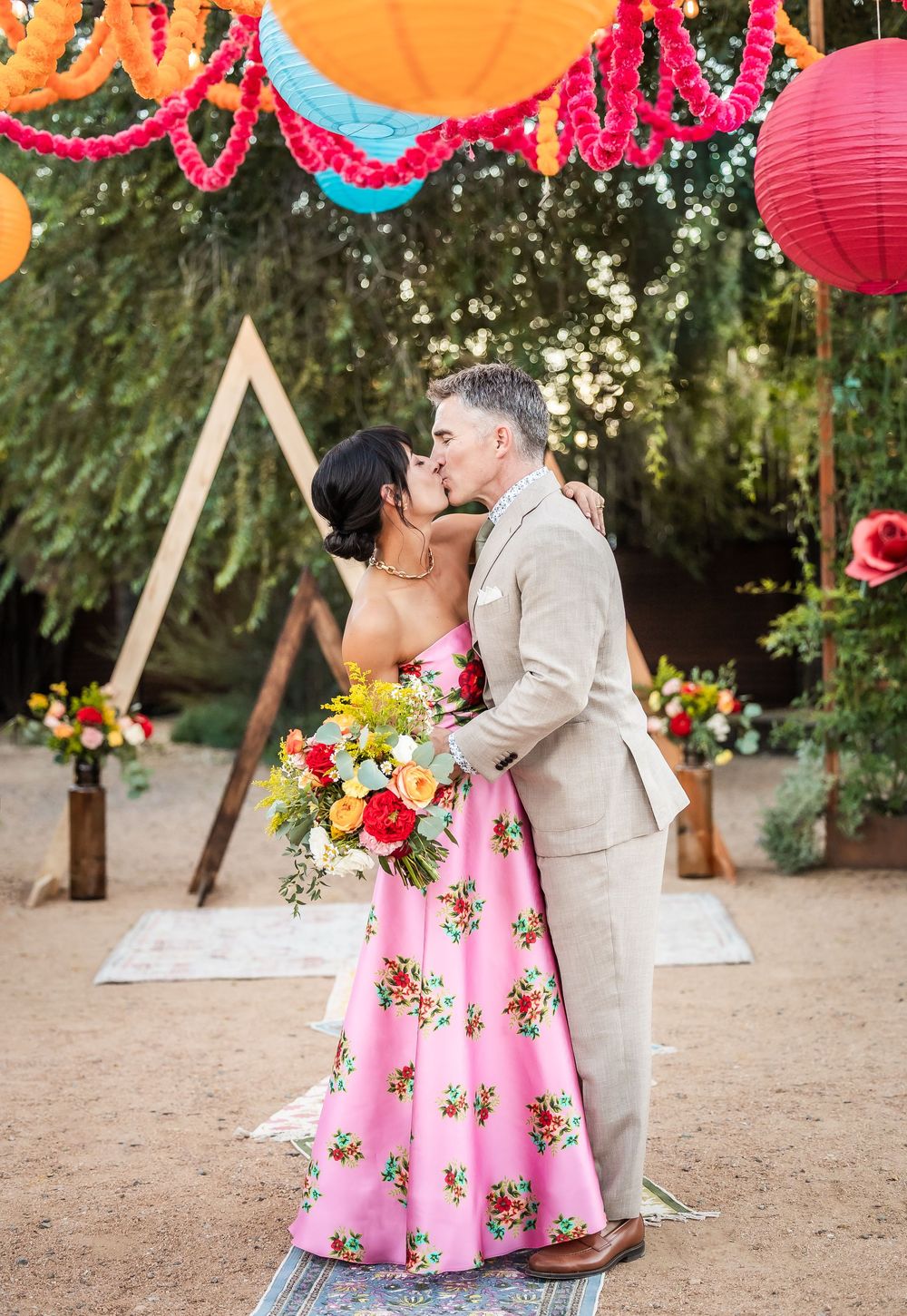 Couple shares romantic moments on outdoor dance floor decorated with colorful paper lanterns and floral arrangements.