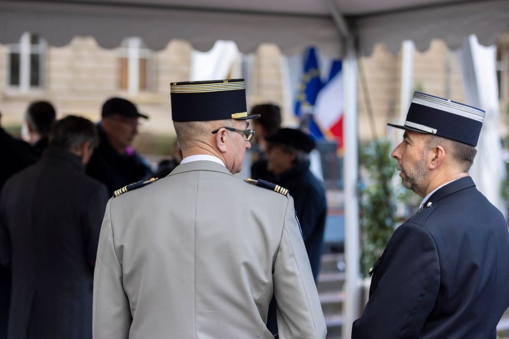 Military officials and dignitaries in formal attire gather at an outdoor public ceremony.