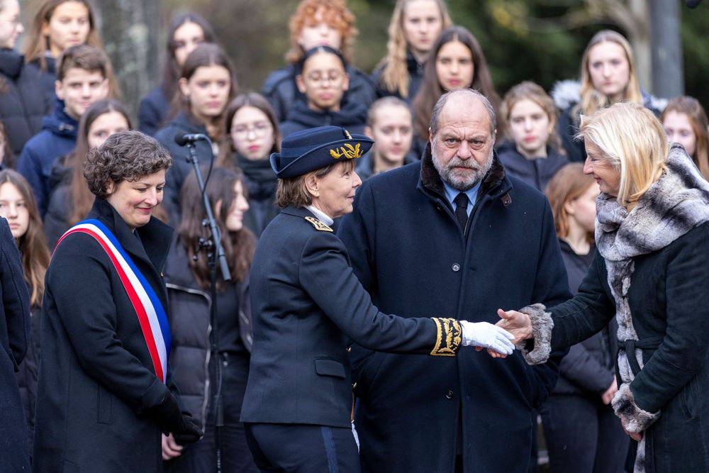 A line of people gathered outdoors during a cold winter day at a solemn public ceremony or memorial service.