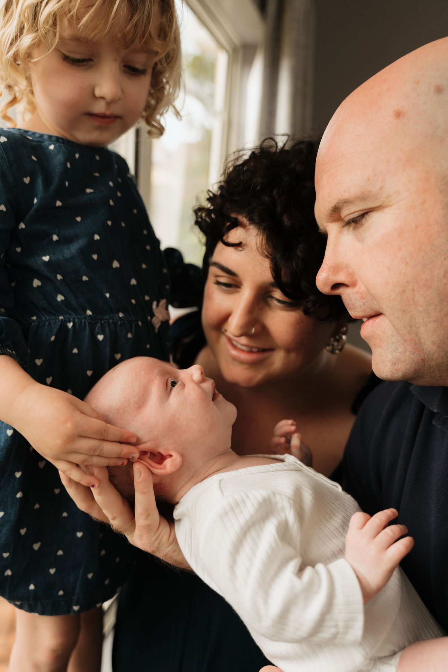 Family gathered around newborn baby in intimate home setting.